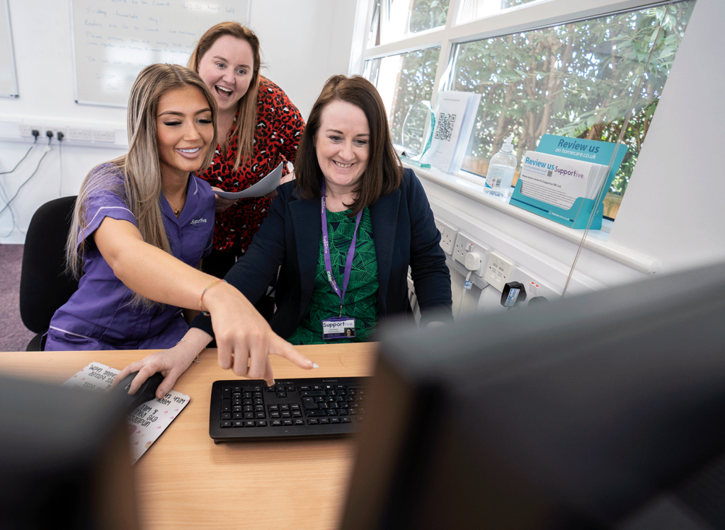 Three staff members working on a computer